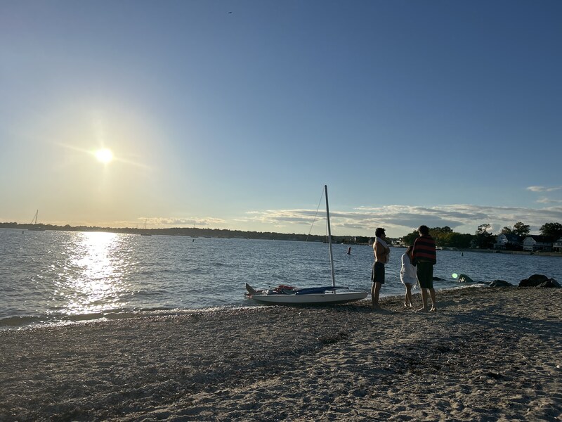 People with a small sailboat on the beach